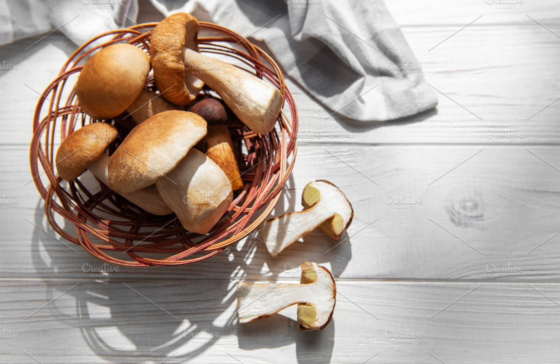 Fresh porcini mushrooms in basket on white wooden background, a Food & Drink Photo by Olena Rudo