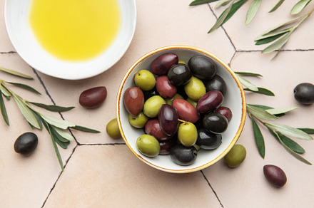 Bowl of assorted olives with olive oil and olive branches on til, a Food & Drink Photo by Olena Rudo