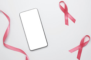 Pink ribbon on smartphone mockup for prevention reminders. Breast cancer awaren, a Photo by matucha