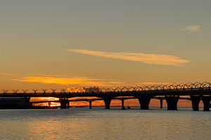 A beautiful sunset over a calm body of water with a bridge silhouetted against, a Nature Photo by Textures & Backgrounds