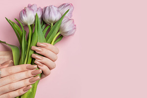Woman holding bouquet of purple tulips showing manicure on pink, a Beauty & Fashion Photo by Olena Rudo