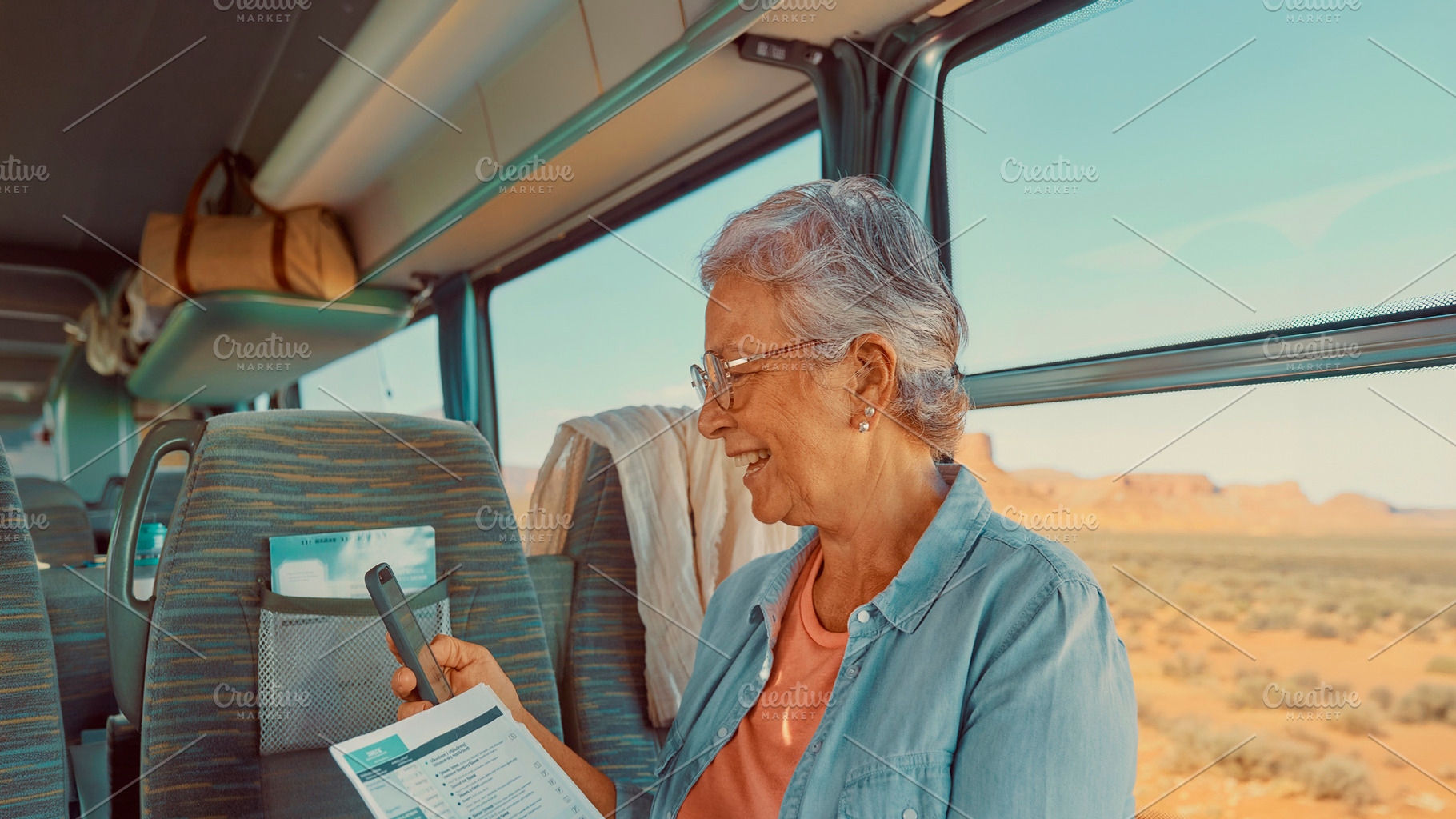 Senior woman sitting by the window inside a moving coach bus, a Person Photo by DanFLCreativo