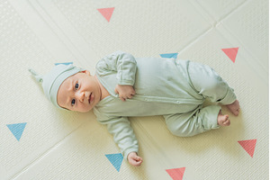 Adorable baby in a green hat lying, a Person Photo by Elizaveta Galitskaya