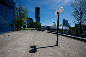 Empty urban plaza with lamp post casting shadow against skyscrapers in Katowice, a Photo by AS photostudio