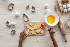Unrecognizable black girl making cookies, top view, a Photo by Prostock-Studio