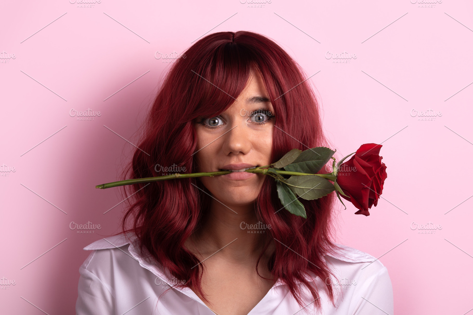 Young woman with red hair holds a single red rose in her mouth a, a Person Photo by Ales Munt