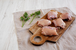 Raw Organic Boneless Skinless Chicken Thighs on a Wooden Board,, a Food & Drink Photo by LiudmylaChuhunova