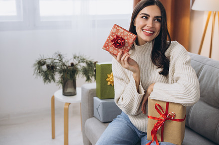 Beautiful happy woman unwrapping New Year or Christmas presents