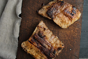 Two pieces of fried meat on an old wooden board, top view, a Food & Drink Photo by ndanko