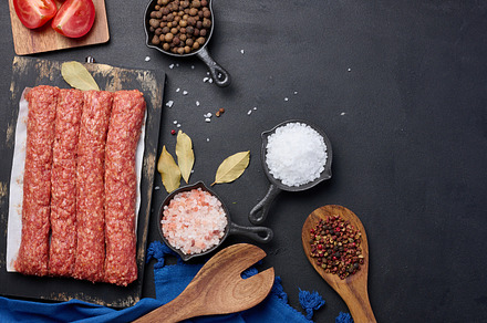 Raw lula kebab sausages on a board and spices, top view, a Food & Drink Photo by ndanko
