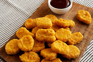 Organic Fried Chicken Nuggets on a wooden board, side view. Copy, a Food & Drink Photo by LiudmylaChuhunova