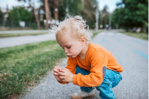 Curious toddler boy examines small, a Nature Photo by HalfPoint