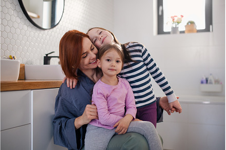 Mother of two little girls hugging, a Person Photo by HalfPoint