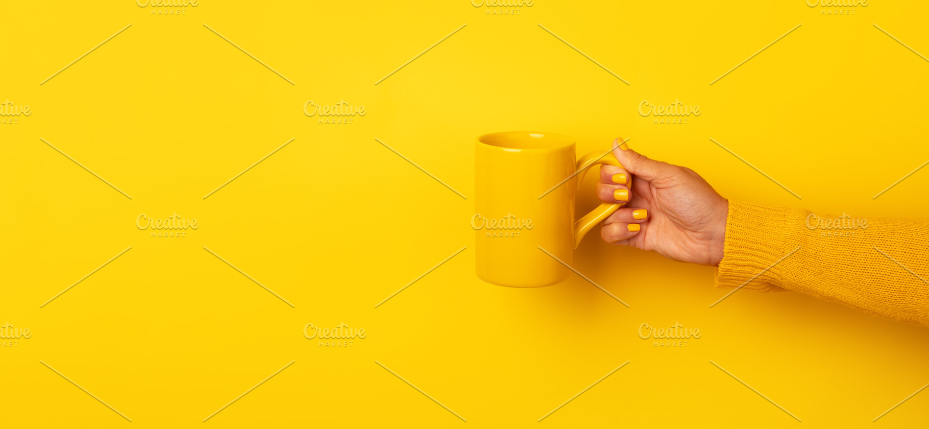 Hand in yellow sweater holding a plain yellow ceramic mug horizo, a Food & Drink Photo by Ales Munt