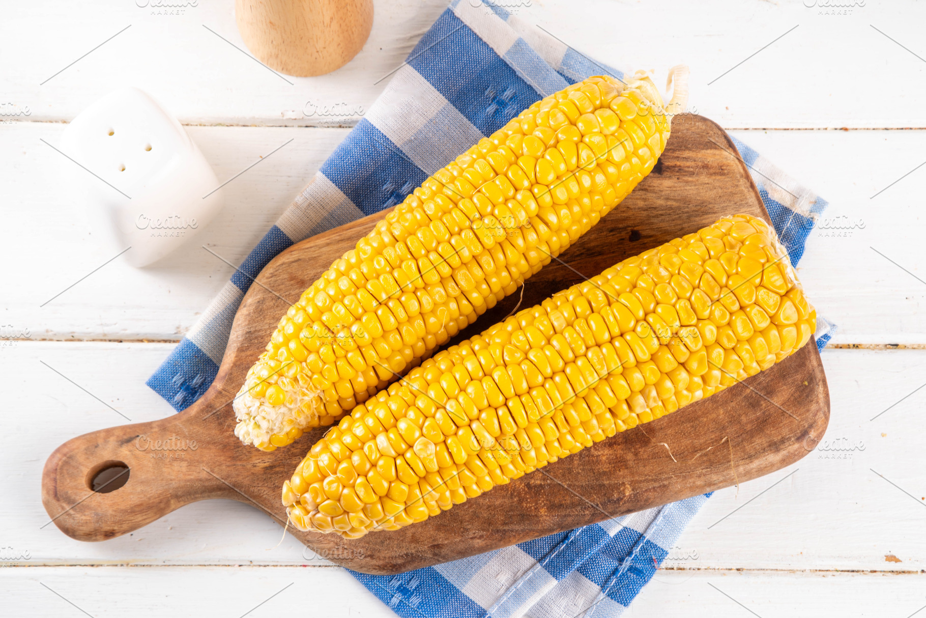 Sweet boiled corn cobs portions on plate, with salt and spices, a Photo by Rimma