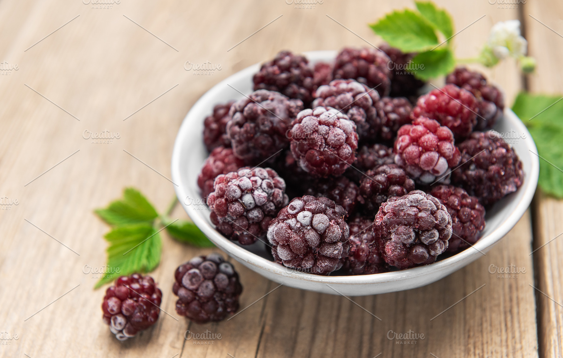 Frozen blackberries in white bowl on wooden background, a Food & Drink Photo by Olena Rudo