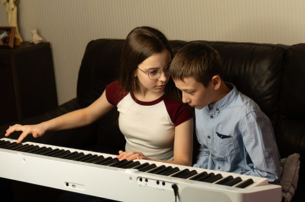 Girl teaching boy to play piano