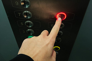 Person pressing elevator button illuminated with red light for eighth floor, a Photo by AS photostudio