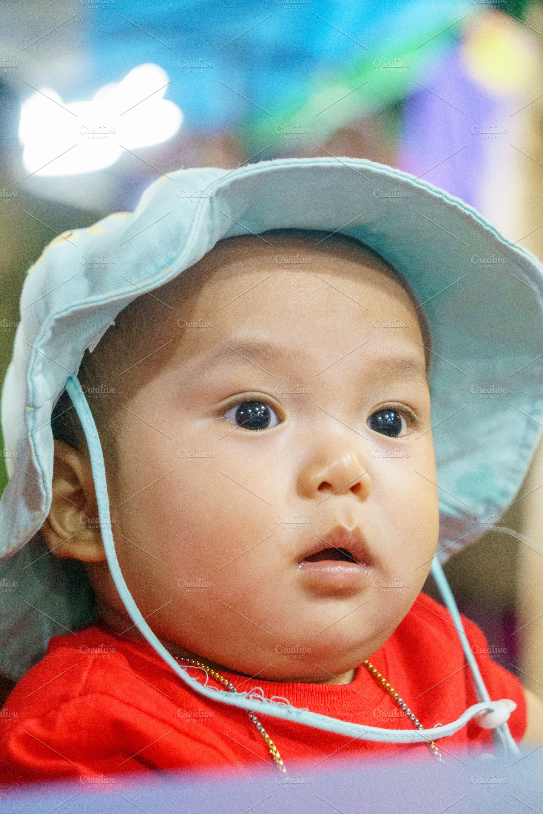 Curious baby wearing blue hat, looking surprised and attentive, a Person Photo by a454
