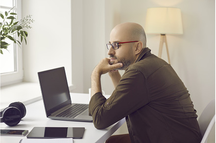 Pensive man sitting at his working, a Technology Photo by StudioRomantic