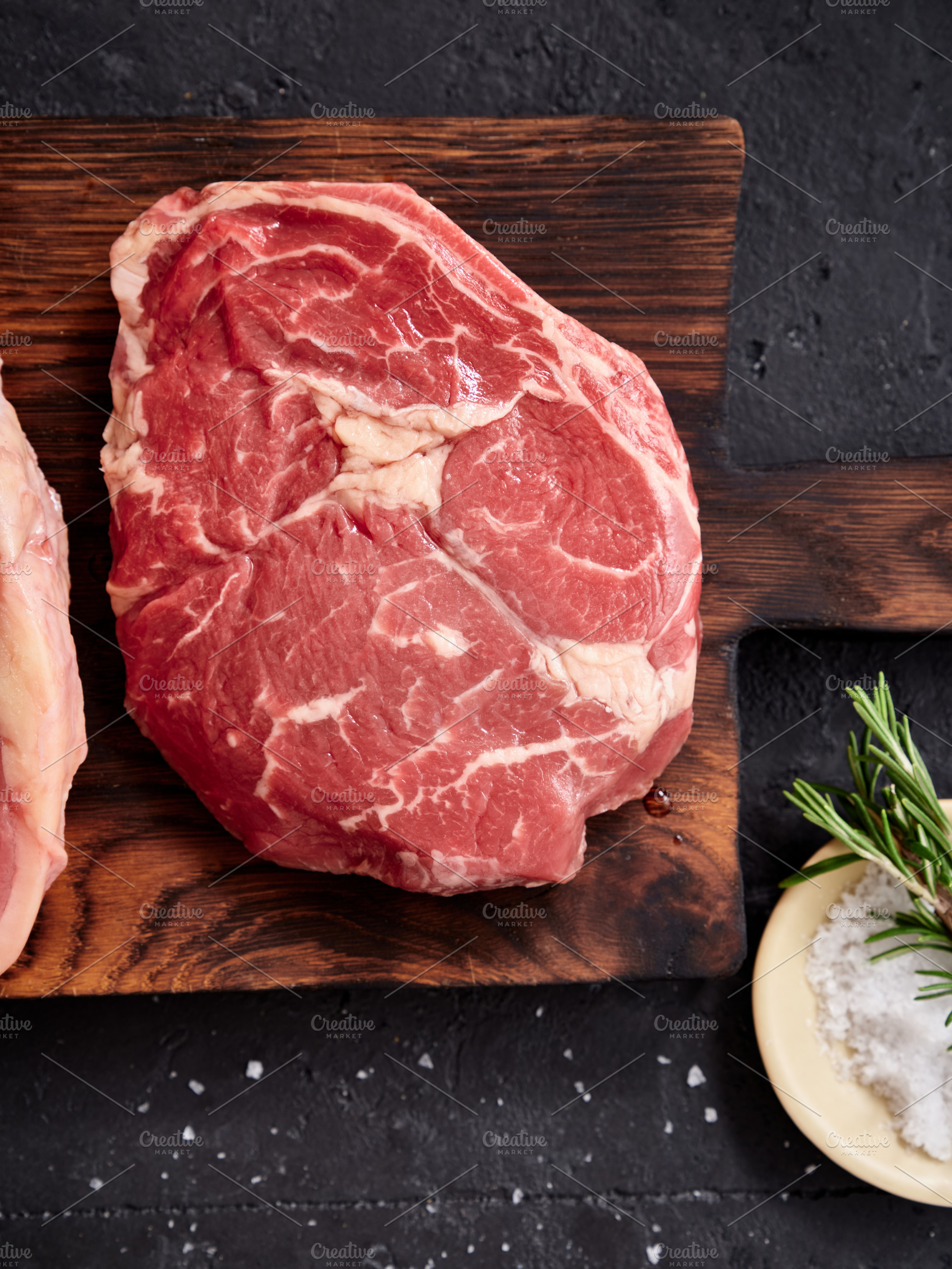 Raw rib-eye steak and other cuts placed on a wooden board with seasoning in a k, a Food & Drink Photo by Asya Nurullina