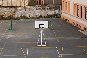Empty outdoor basketball court with a net and building in the ba