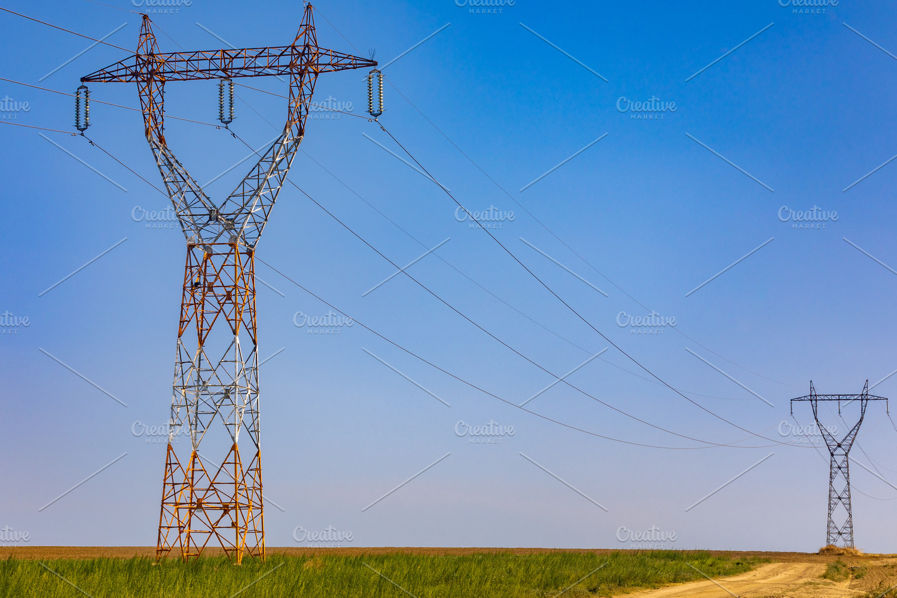 Tall electricity pylons stretch across an open rural landscape under a clear bl, a Technology Photo by Ales Munt