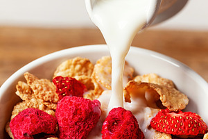 Pouring milk into bowl of cereals with dehydrated raspberries and strawberries, a Food & Drink Photo by Antonio Gravante Market