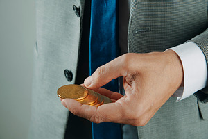 businessman holding golden bitcoin tokens, a Photo by Nito