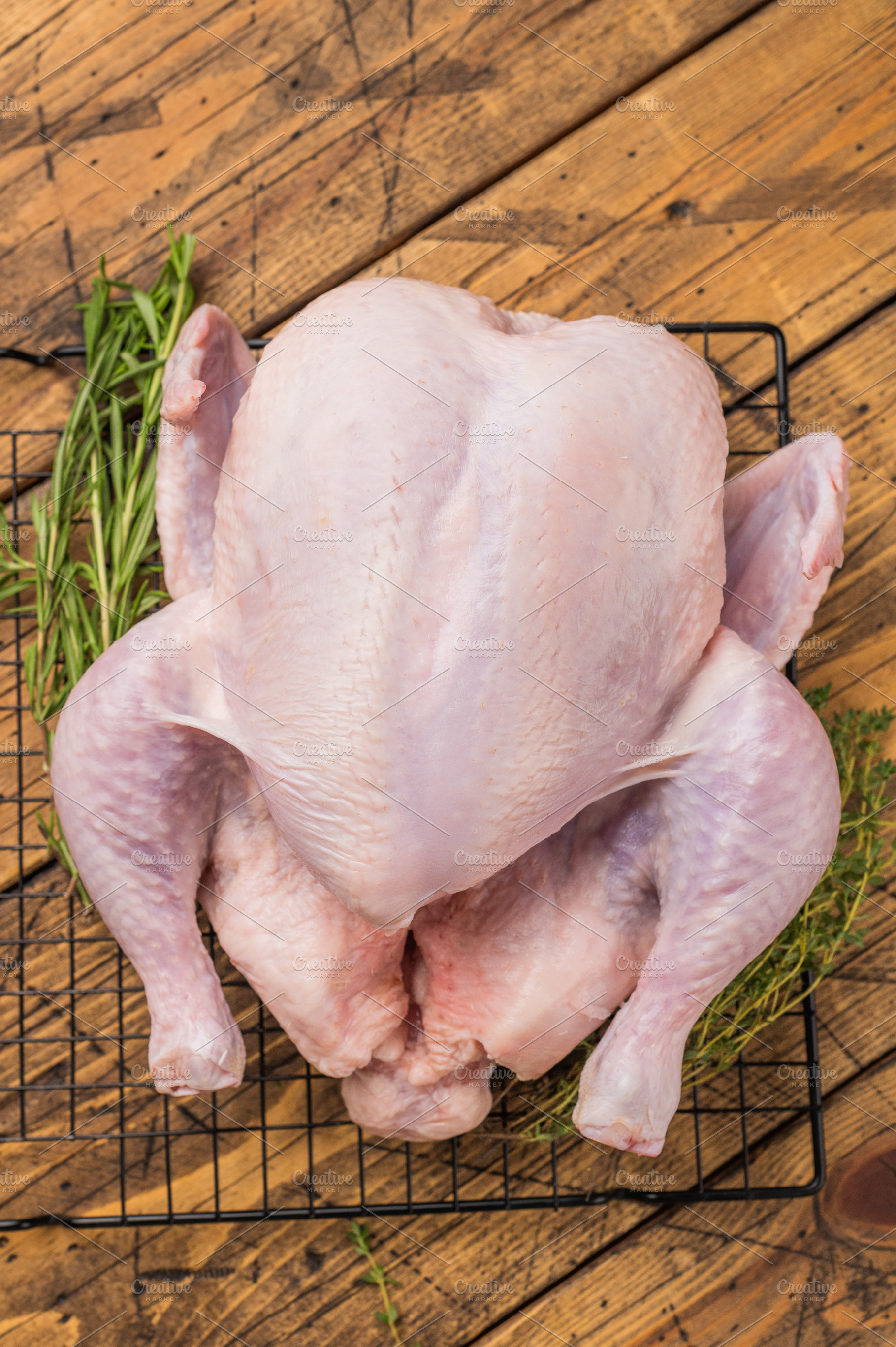 Whole fresh raw chicken on a cooling rack with rosemary and thym, a Photo by composter-box@mail.ru