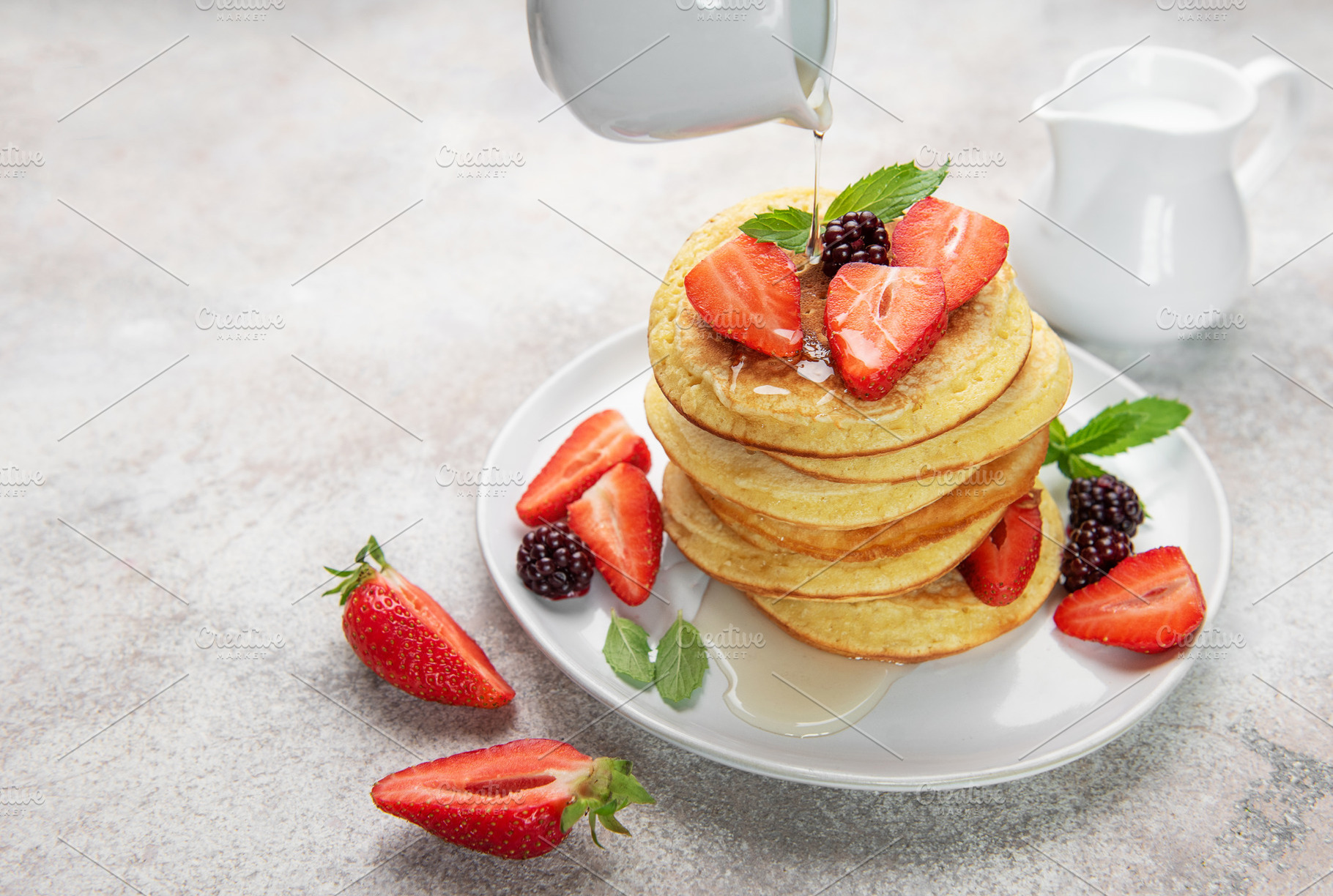 Pancakes with berries and syrup pouring for breakfast, a Food & Drink Photo by Olena Rudo