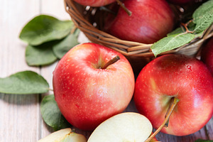 Red organic apples in basket with fresh green leaves, a Food & Drink Photo by Olena Rudo
