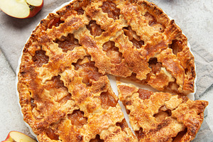 Freshly baked apple pie with a slice missing and apples beside, a Food & Drink Photo by Olena Rudo