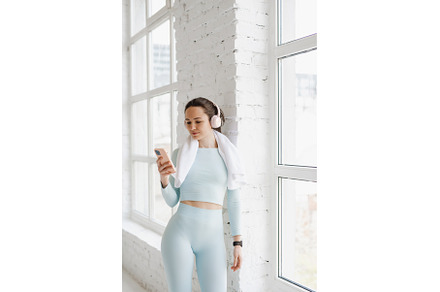 Sporty young woman using smartphone, a Sports & Recreation Photo by Aliona Serzhanova