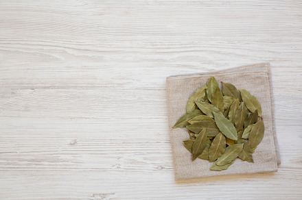 Raw Bay Leaves on a white wooden background, top view. Flat lay,, a Food & Drink Photo by LiudmylaChuhunova