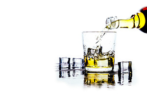 Whiskey pours from a bottle into a g