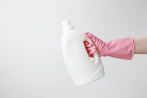 Female hand in a pink rubber glove holding a white branding mockup of laundry g, a Photo by matucha