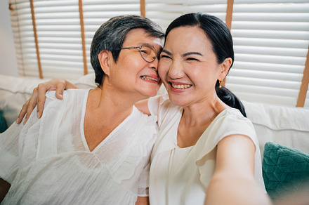Asian mother and daughter taking selfie at home