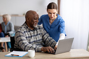 Young woman nurse helping black senior man using laptop, a Photo by Prostock-Studio (Thumbnail 2 of 2)