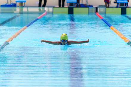Swimmer child swims butterfly swimming style in a race swimming