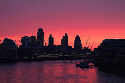 Vibrant sunset over a city skyline w, a Photo by Tanuart