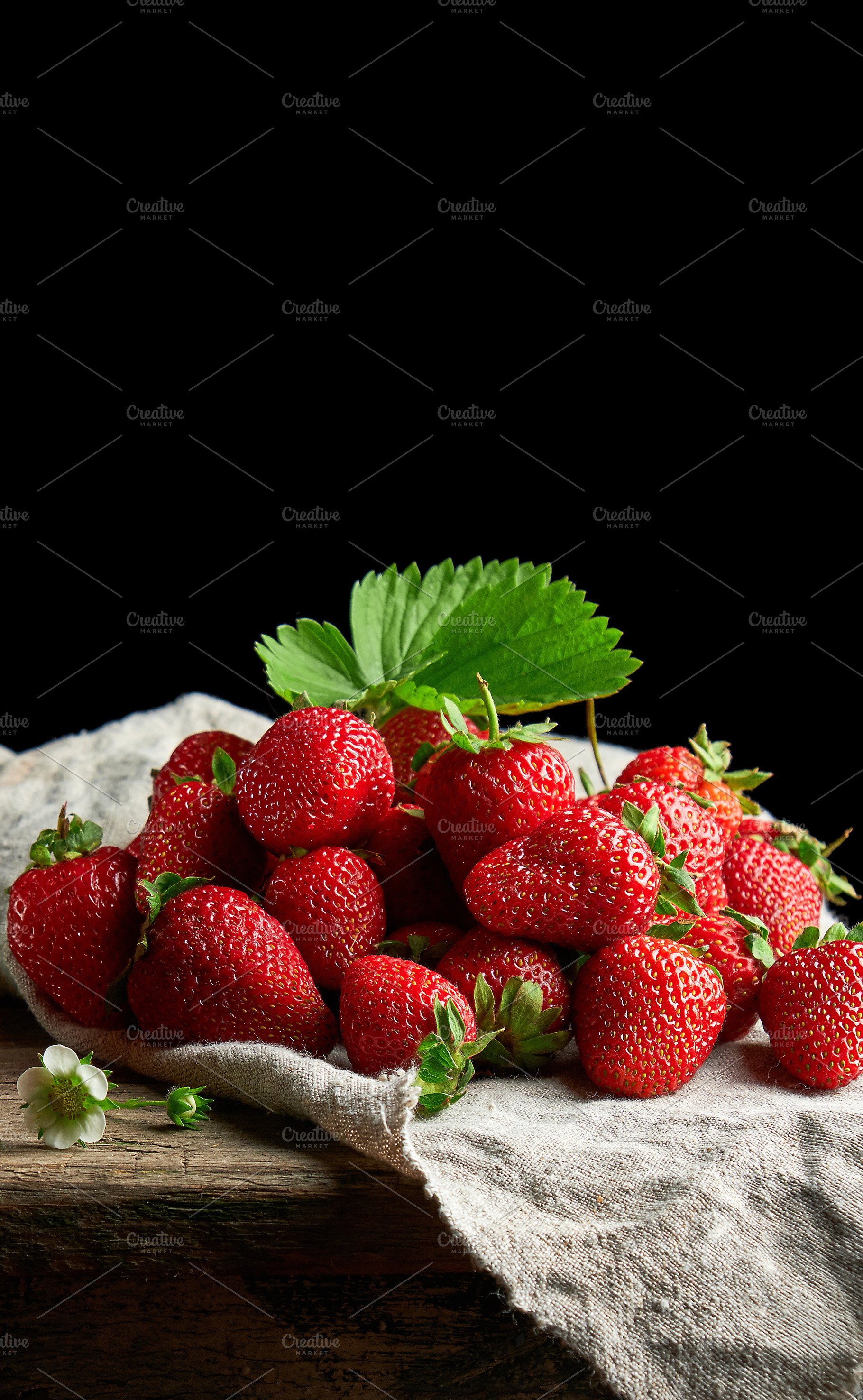Ripe juicy strawberries with leaves on a linen napkin and wooden, a Food & Drink Photo by ndanko