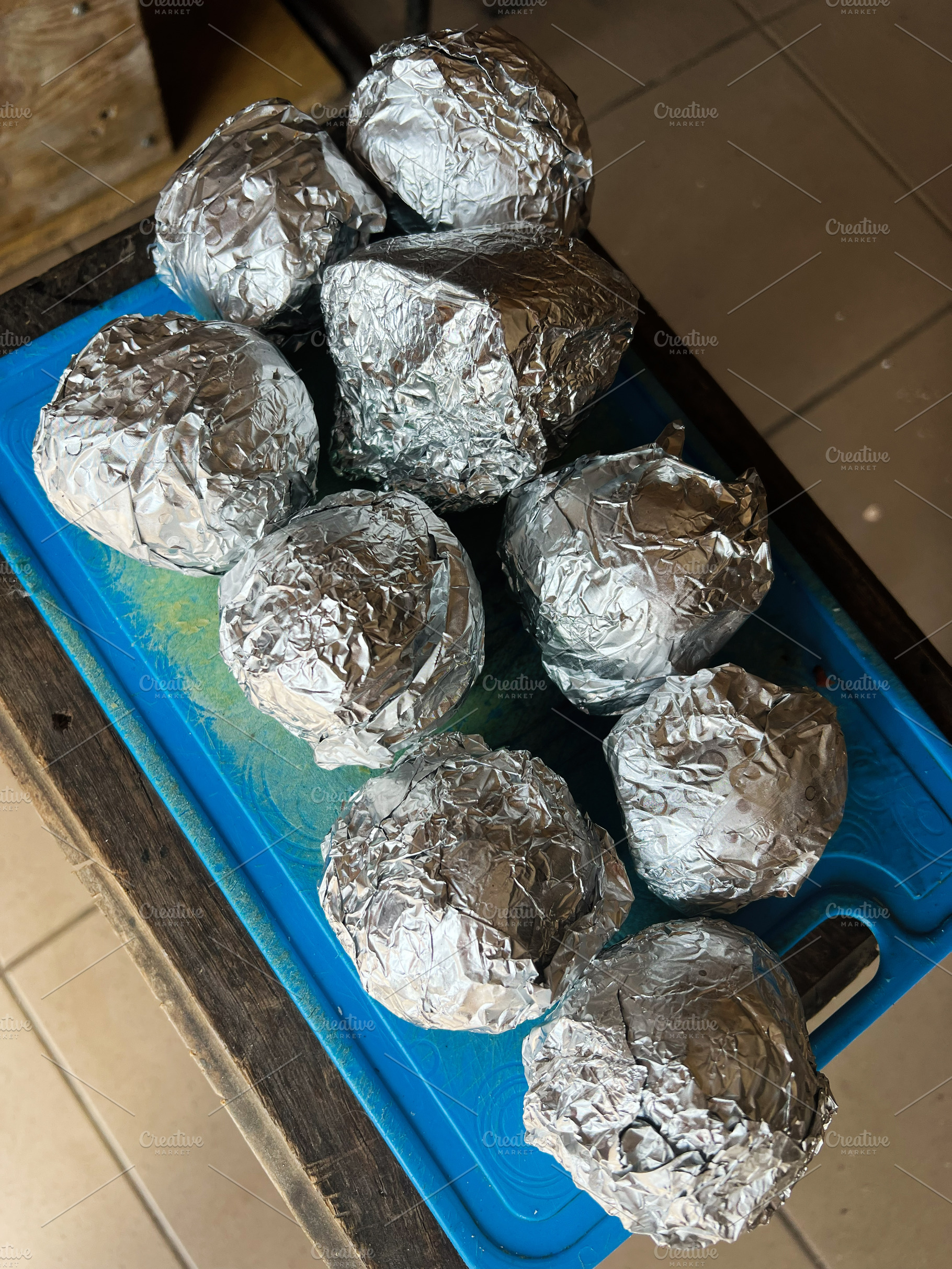 Foil Wrapped potato Arranged on a Blue Surface with Tiled Background, a Photo by AS photostudio