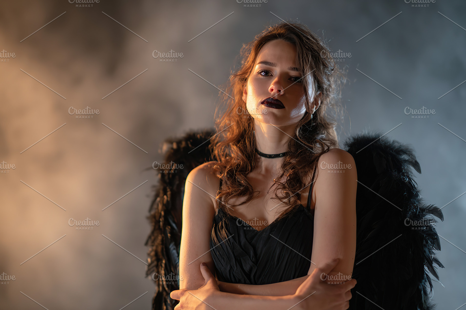 Mysterious woman with black wings poses in dramatic lighting during a creative, a Photo by AlyaAnd