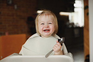 Infant girl or toddler sitting on high chair. Eating food by herself using spoo, a Person Photo by Lenor4ik