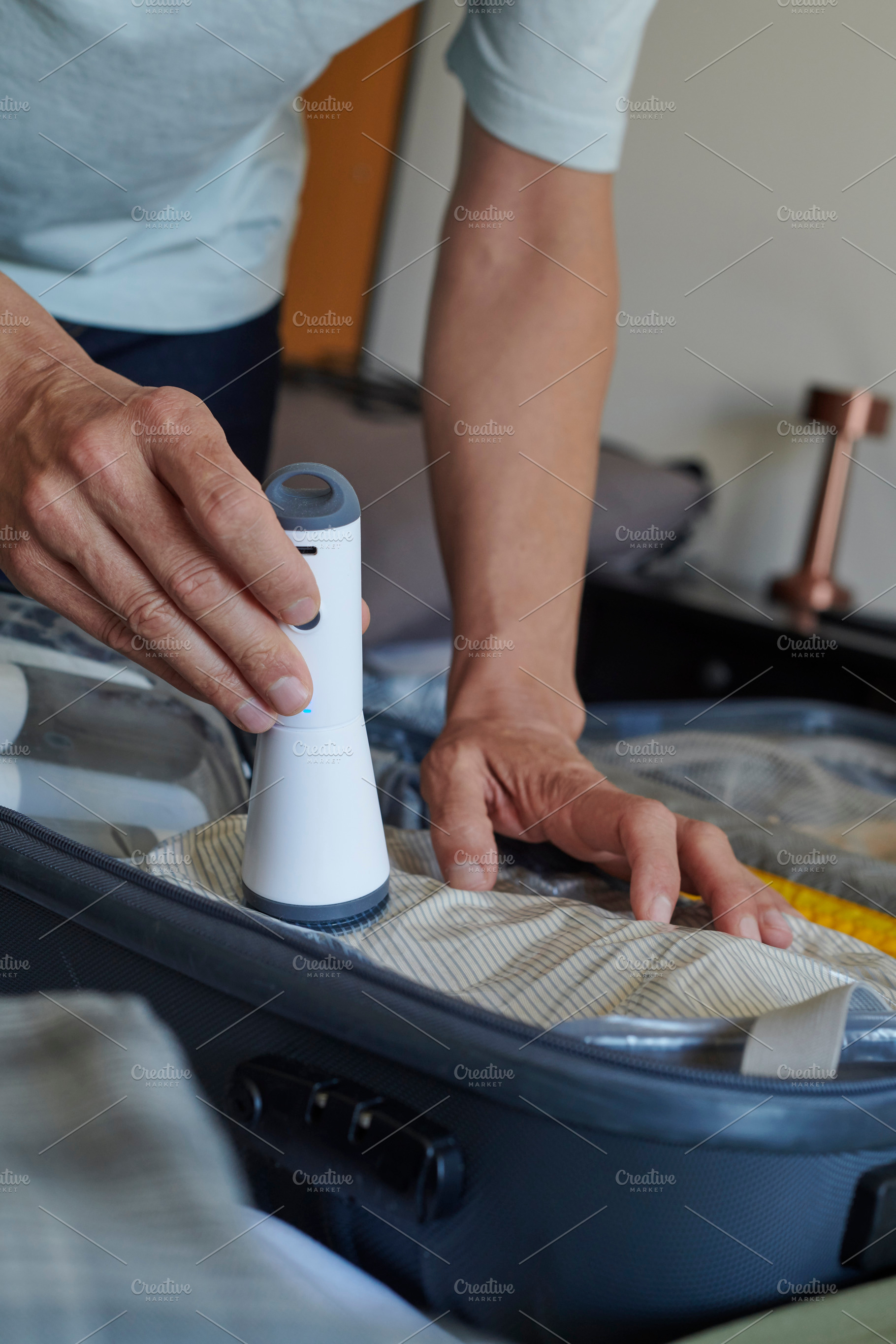 man using a vacuum pump to store clothes in a bag, a Photo by Nito