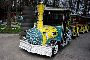 Colorful illuminated train cart in a park setting during daytime, a Photo by AS photostudio