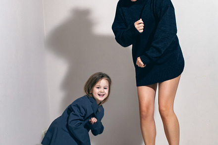 funny portrait of a fashionable girl child in a large gray jacket stands agains, a Person Photo by SaulichPhoto