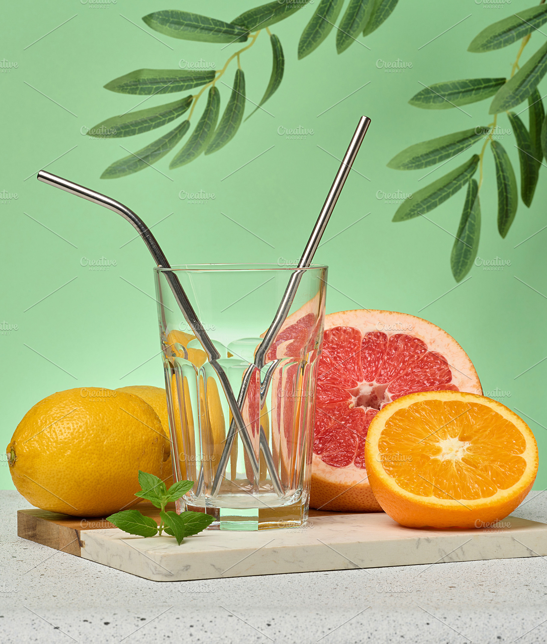 Grapefruit, orange and empty glass on green background, a Photo by ndanko
