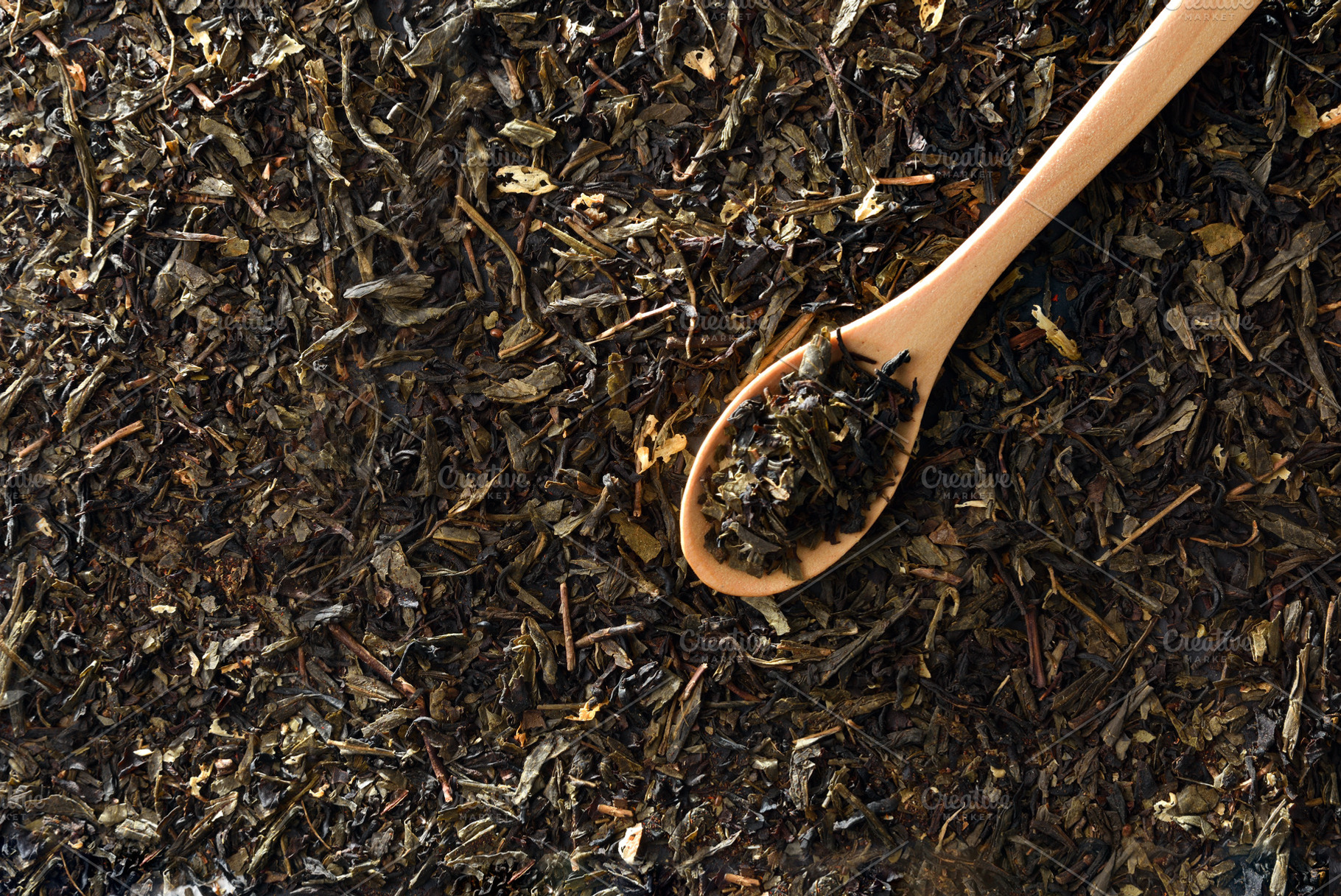 Wooden spoon filled with tea leaves on background tea top, a Food & Drink Photo by Davizro's Market